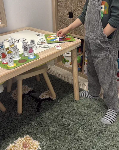 Copil la măsuța de joc, așezând jetoane și figurine în timpul unei activități ghidate la cabinetul de logopedie din Timișoara
