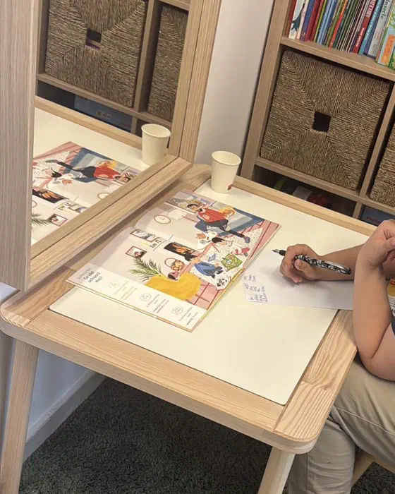 Copil lucrând cu o carte cu imagini la măsuța din cabinetul de logopedie din Timișoara, în timpul unei ședințe prin joc